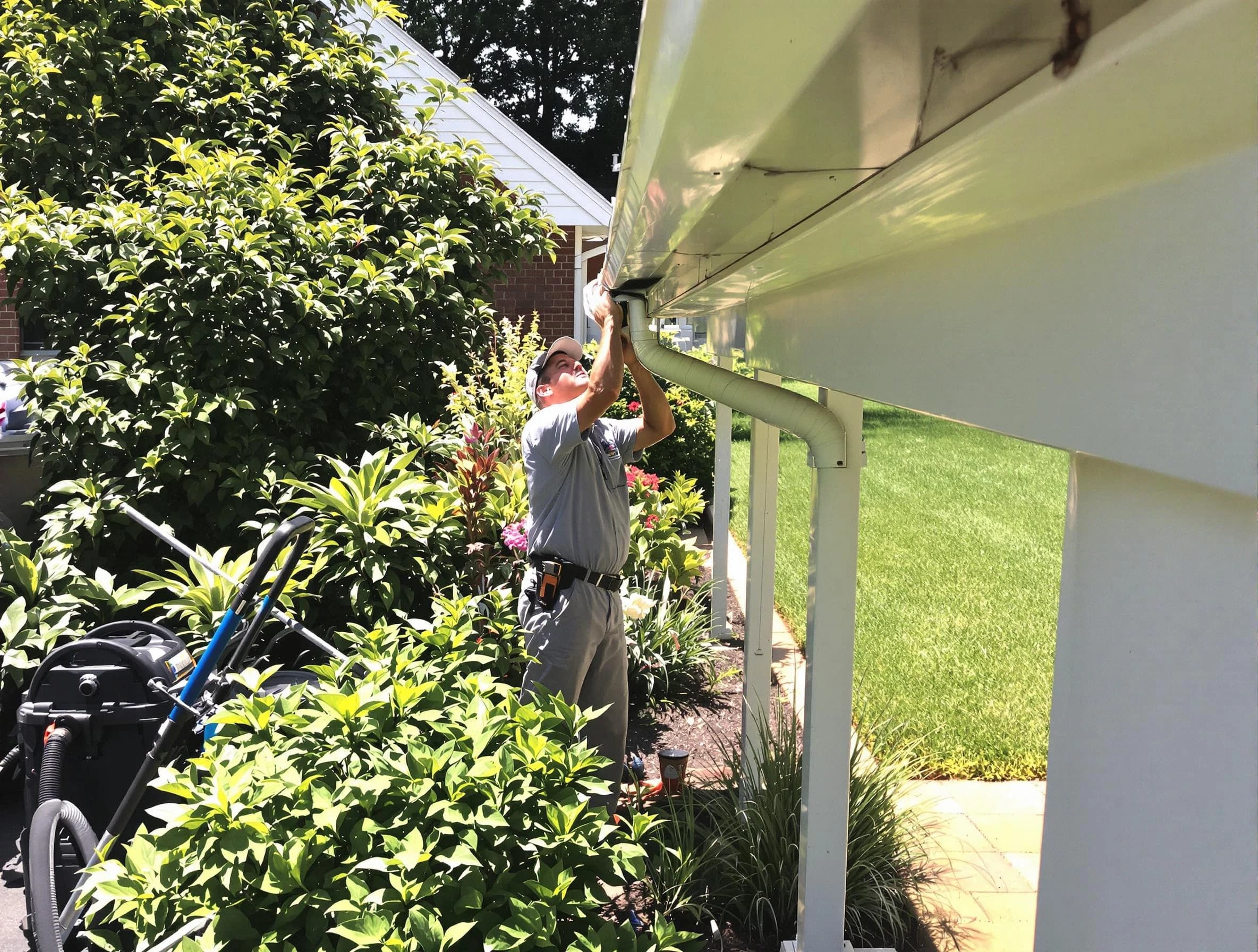 Technician flushing a blockage from a downspout in University Heights, OH